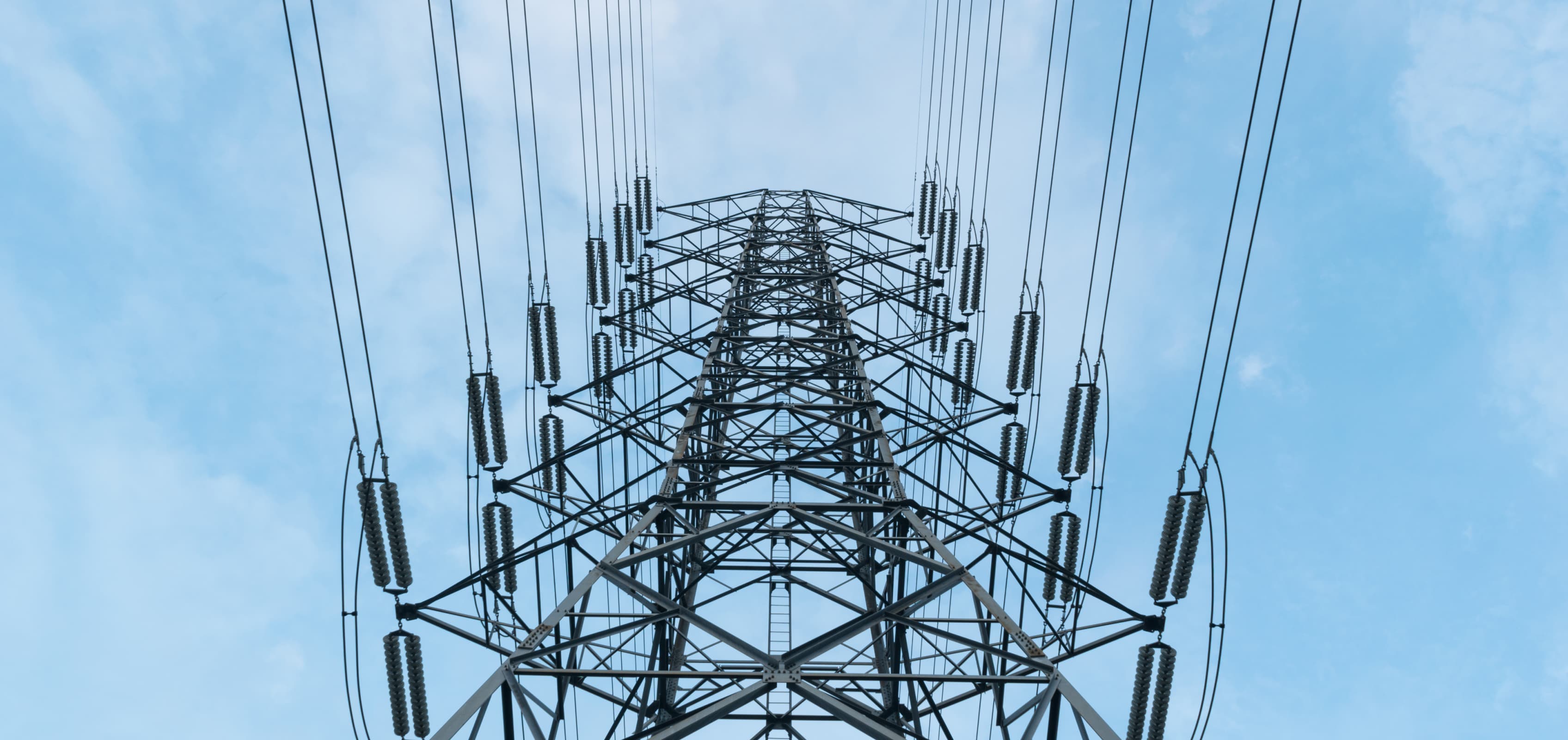 Looking up at a transmission tower against a clear sky